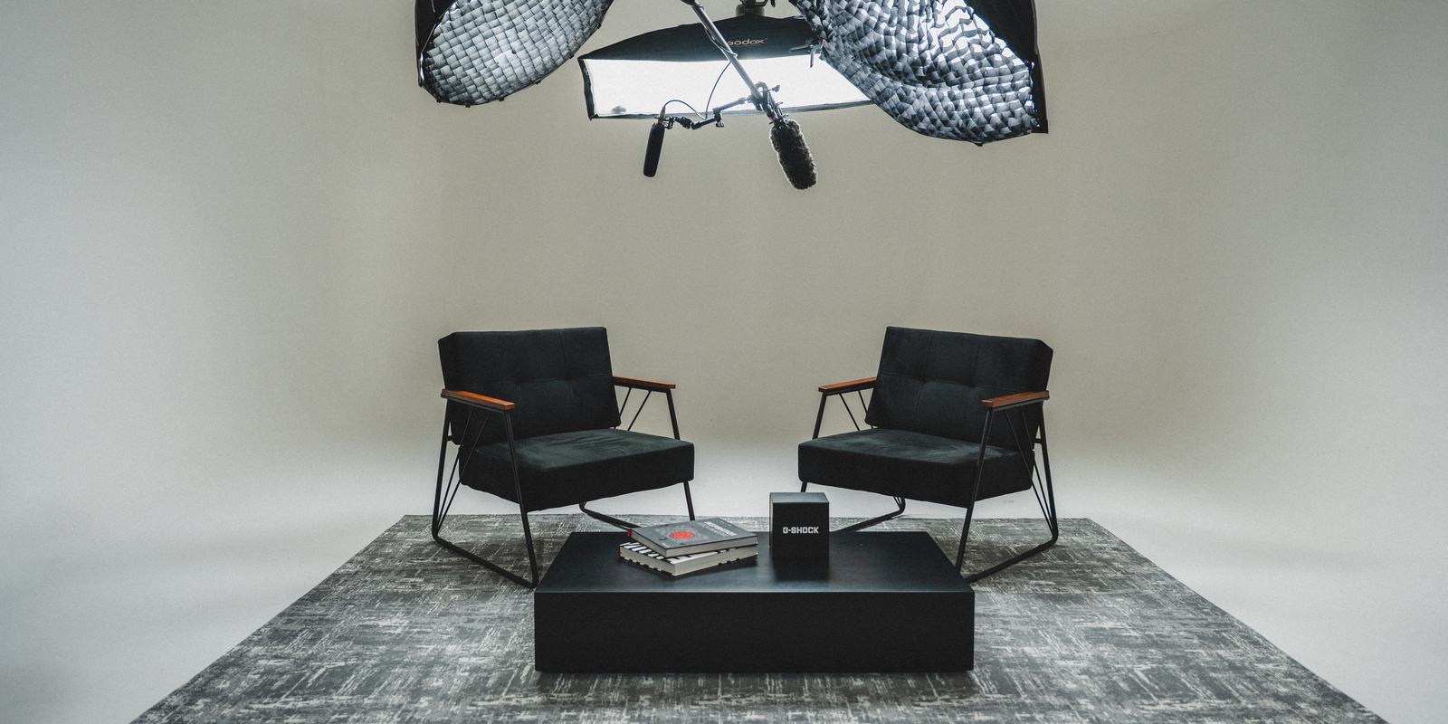 Set montado no fundo infinito de 270° do Studios Firma, com duas poltronas, tapete e luzes suspensas